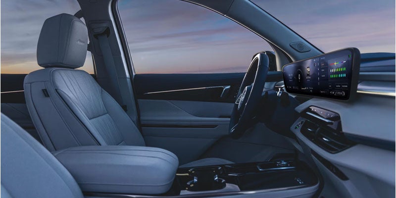 Front cabin view with driver seat, steering wheel, and digital display.